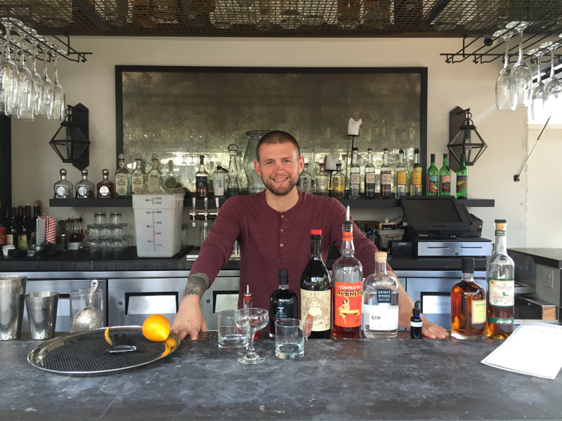 Eisner behind the bar with his CBD oil in the tiny blue bottle